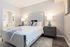 Modern bedroom with plush bedding, stylish decor, and ambient lighting.