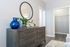 Stylish bedroom corner with a sleek wooden dresser, decorative mirror, and vibrant blue vase.