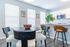 Bright dining room with round black table and modern chairs, adjacent to a stylish kitchen with white cabinetry and bar seating.