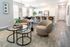 Modern open-concept living and kitchen area with plush seating, sleek bar stools, and decorative plants.