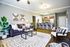 Bright and stylish open-concept living space with modern furniture, plant decor, and a sleek kitchen island with bar stools.