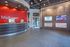 Sleek reception area with a curved desk, bold red accent wall, and digital displays.