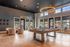 Stylish lounge room with modern decor, featuring a pool table, circular chandeliers, and large windows.