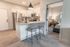 Modern apartment kitchen with granite countertops, stainless steel appliances, and cozy dining stools.
