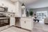Modern kitchen with sleek stainless steel appliances and open-concept living room with large window and cozy decor.