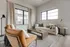 Bright and modern living room with a plush sofa, elegant armchair, and large windows offering natural light.