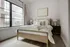 Inviting bedroom with a cozy bed, stylish decor, and large window offering natural light.