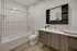 Sleek bathroom with a contemporary design featuring a white bathtub, stylish wooden vanity, and modern mirror.
