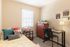 Inviting bedroom with natural light, colorful pillows, a desk, and stylish decor.