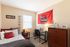 Bright student bedroom featuring a comfy bed, study desk, and vibrant university decor.