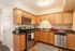 Modern kitchen with stainless steel appliances, wooden cabinets, and sleek black countertops.