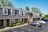 Row of charming brick townhomes with dormer windows and adjacent parking spaces.