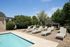 Inviting pool area with comfortable loungers and lush greenery under a clear blue sky.