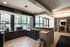Bright community lounge featuring large windows, a kitchenette with modern appliances, and a cozy library area.
