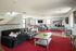 Spacious modern lounge with comfortable seating, vibrant red accents, and large windows.