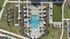 Aerial view of a stunning outdoor pool surrounded by palm trees, lounge chairs, and green recreational spaces.