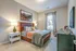 Inviting bedroom with plush bed, elegant decor, and ample natural light from a large window.