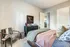 Cozy bedroom with elegant decor, featuring chic artwork, a plush bed, comfortable armchair, and warm natural lighting.