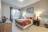 Inviting bedroom with plush beige carpet, stylish decor, and abundant natural light from large window.