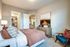 Inviting bedroom with cozy bedding, elegant decor, and a walk-in closet, showcasing modern comfort and style.