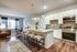 Elegant open-layout apartment featuring a modern kitchen with granite countertops, stylish bar stools, and an inviting living area with large windows and cozy seating.