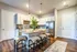 Modern kitchen with elegant white cabinetry, spacious granite island, and stylish bar stools. Features sleek stainless steel appliances and warm wood flooring, ideal for entertaining and daily living.