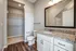Elegant bathroom with modern fixtures, granite countertop, ample closet space, and pristine wood flooring.