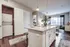 Elegant apartment kitchen with granite island, modern pendant lights, and view of inviting living area with natural light.