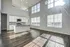 Bright and airy living space with high ceilings, large windows, and a modern kitchen featuring granite countertops and stainless steel appliances.