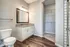 Bright and modern bathroom with granite countertops, large mirror, and spacious walk-in closet.