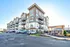 Modern apartment complex with stylish facades, spacious balconies, and ample parking under a clear sky.