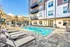 Inviting outdoor pool area at a modern apartment complex, featuring comfortable lounge chairs and shaded seating for relaxation.