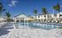 Luxurious outdoor swimming pool with sun loungers and palm trees, set against a backdrop of stylish modern apartments.