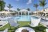 Luxurious pool area with modern seating, surrounded by palm trees and elegant white loungers under sunny blue skies.