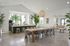 Bright and airy dining space featuring a modern kitchen with a long wooden table and stylish seating, bathed in natural light.