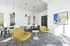Modern meeting room with vibrant yellow chairs, stylish white tables, and contemporary artwork, perfect for creative collaboration.