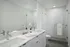 Elegant modern bathroom featuring a sleek double sink vanity, large mirror, and glass-enclosed shower with pristine white tiles.