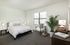 Bright and inviting bedroom featuring a cozy bed, modern decor, and natural light from large windows, perfect for relaxation.