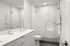 Elegant modern bathroom with sleek white fixtures, spacious shower, and polished tile walls offering a luxurious retreat.