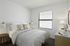 Bright and cozy bedroom featuring a comfortable bed, stylish accents, and ample natural light through large window blinds.