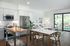 Bright open-concept kitchen and living area with modern appliances, cozy seating, and a view of the lush outdoor patio.