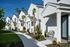 Charming row of modern white townhouses with lush landscaping and inviting walkways, perfect for serene living.