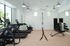 Modern fitness center with treadmills, stationary bike, weight bench, and natural light from large windows.