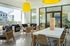 Bright and inviting communal area featuring modern seating, vibrant decor, and elegant wooden furniture with large windows overlooking lush greenery.