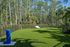 Tranquil outdoor area with lush green lawn, a white bench, and beautiful forest view, perfect for relaxation.