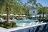Luxurious outdoor pool area with elegant lounge chairs, lush palm trees, and serene ambiance, perfect for relaxation and leisure.