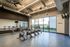 Modern fitness room with stationary bikes, sleek mirrors, and expansive urban view.