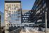 Modern apartment building with multiple balconies and a spacious rooftop terrace featuring white seating, perfect for urban living.