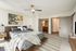 Bright and modern bedroom with elegant decor, featuring a cozy bed, artistic wall art, and a sleek ceiling fan.