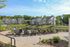 Charming apartment complex surrounded by lush greenery, featuring a serene pond and inviting outdoor seating area.